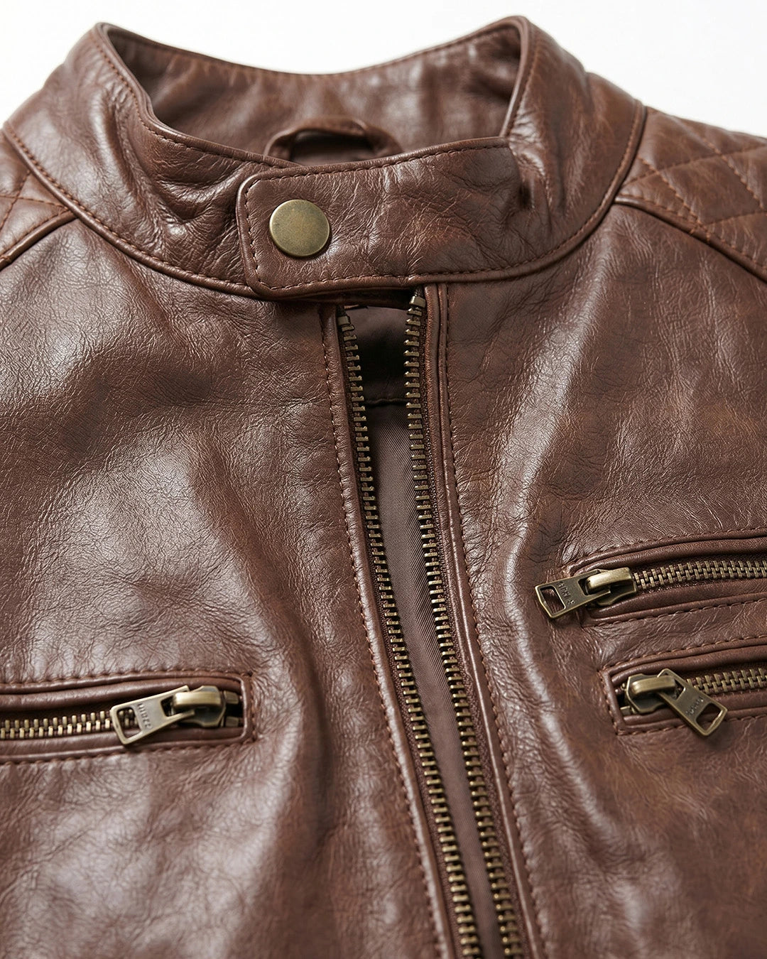 Close-up of a brown leather jacket with gold zippers and buttons.