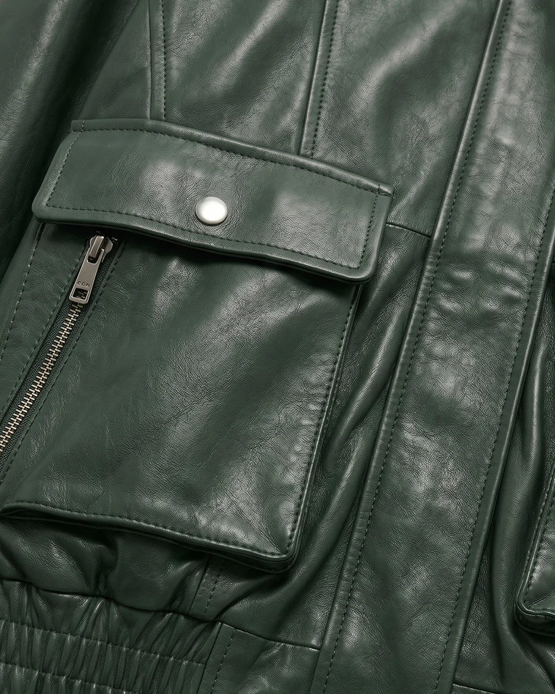 Close-up of a green leather jacket with a pocket and zipper.