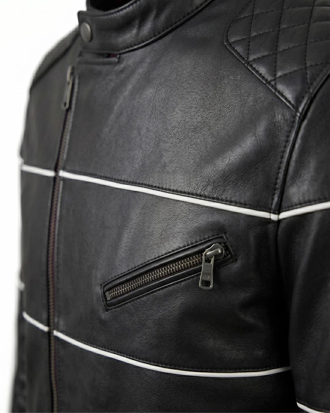 Close-up of a black leather jacket with white stitching and zippers on a gray background