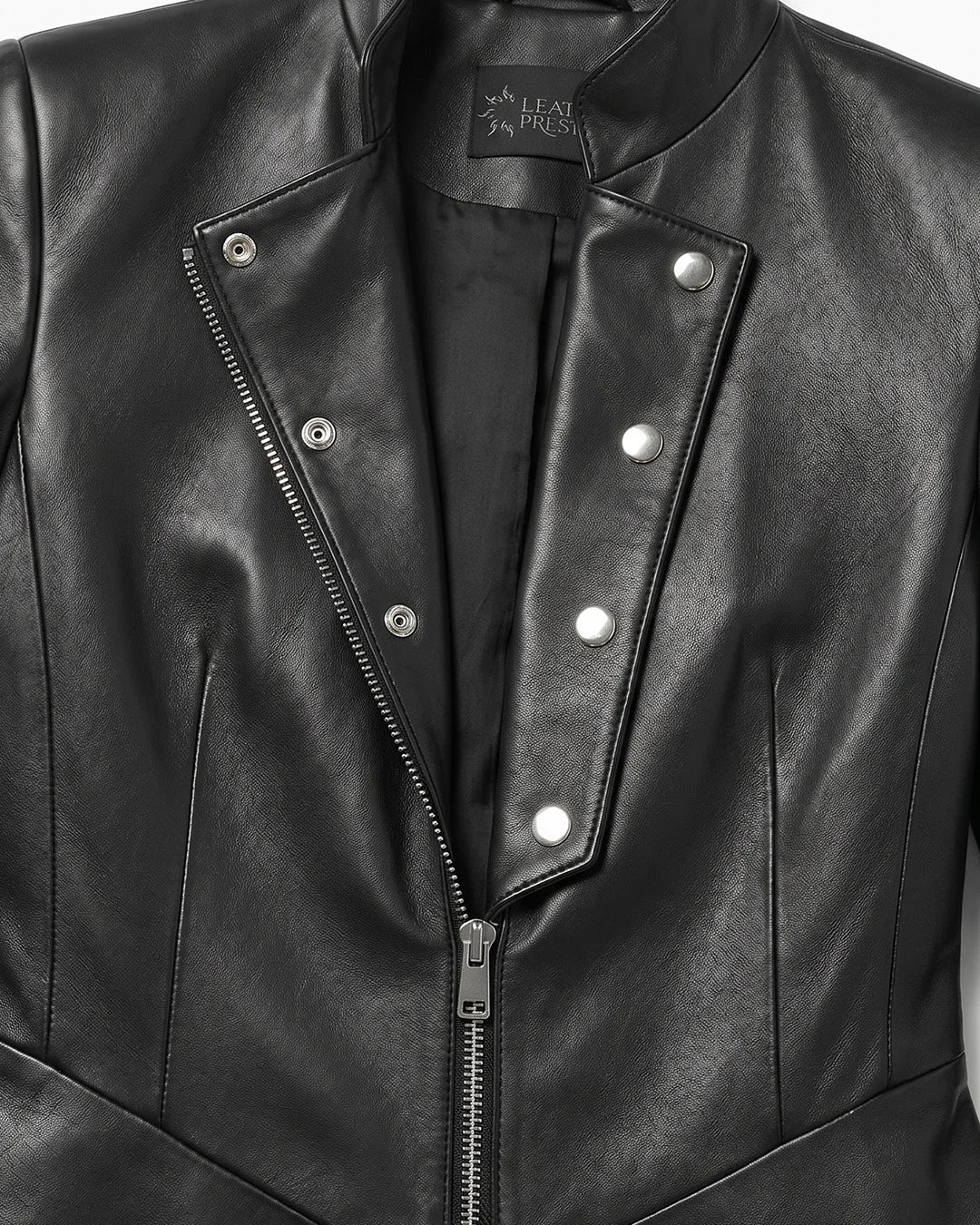 Close-up of a black leather jacket with a brand label on a neutral background