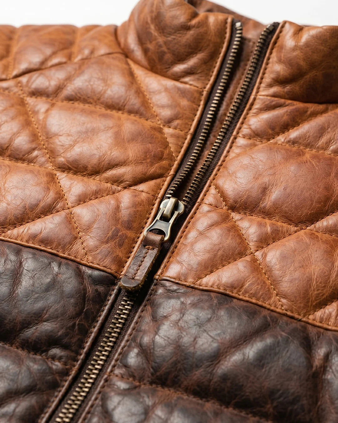 Close-up of a brown quilted leather jacket with a zipper.