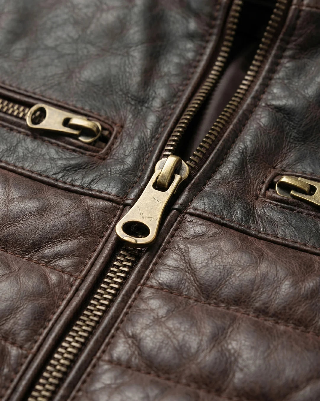Close-up of a brown leather jacket with gold zipper