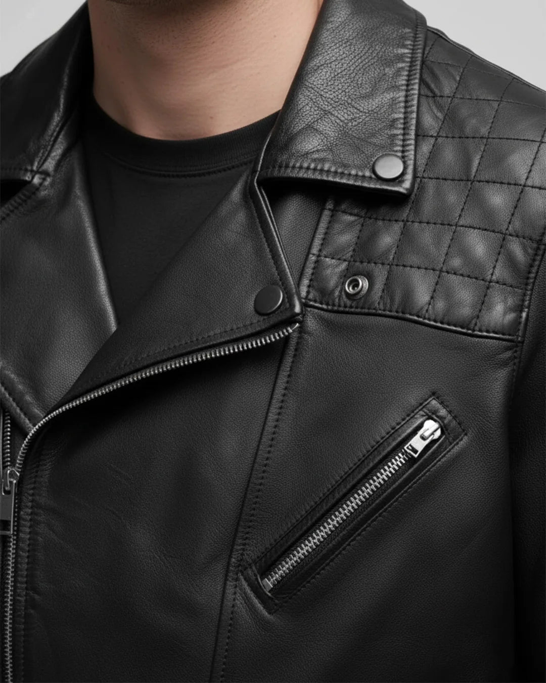 Close-up of a black leather jacket with quilted collar and zipper details.