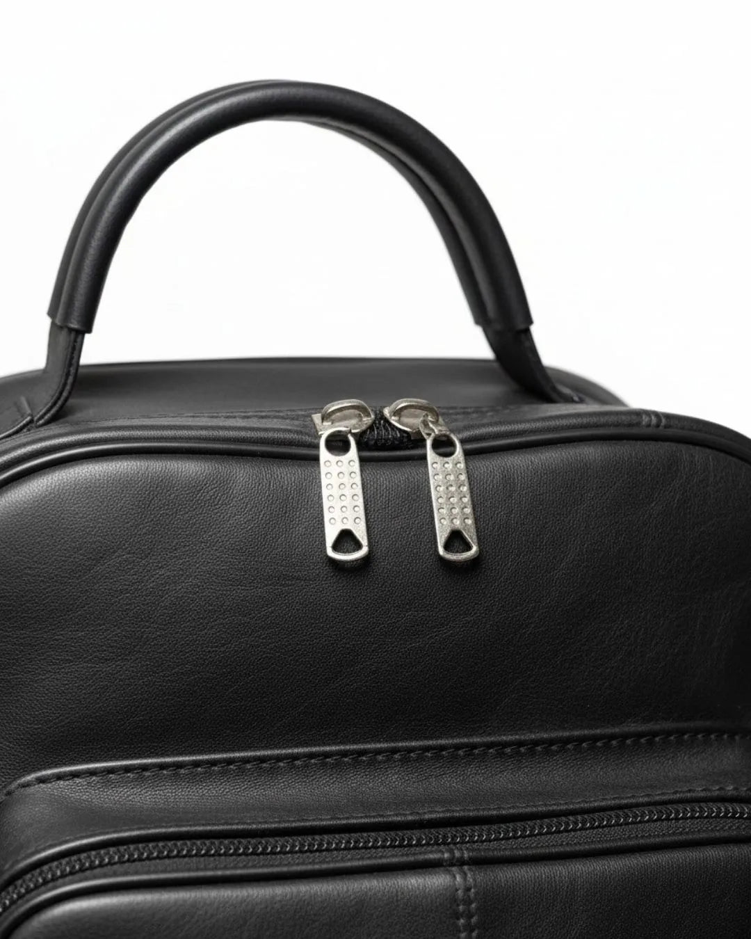 Black leather handbag with silver zippers on a white background