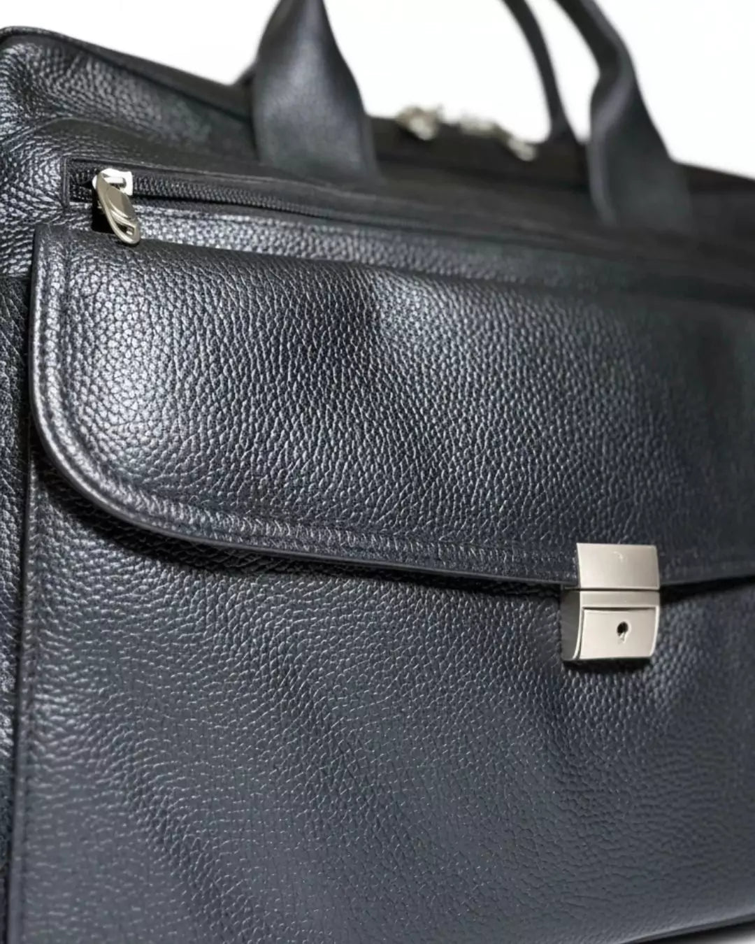 Close-up of a black leather briefcase with a silver clasp on a white background